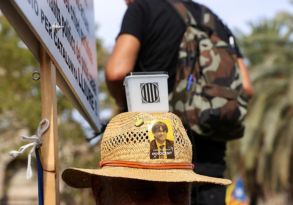 Un manifestante, ayer en la convocatoria independentista con motivo de la Diada, con una imagen de Carles Puigdemont y una urna en su sombrero