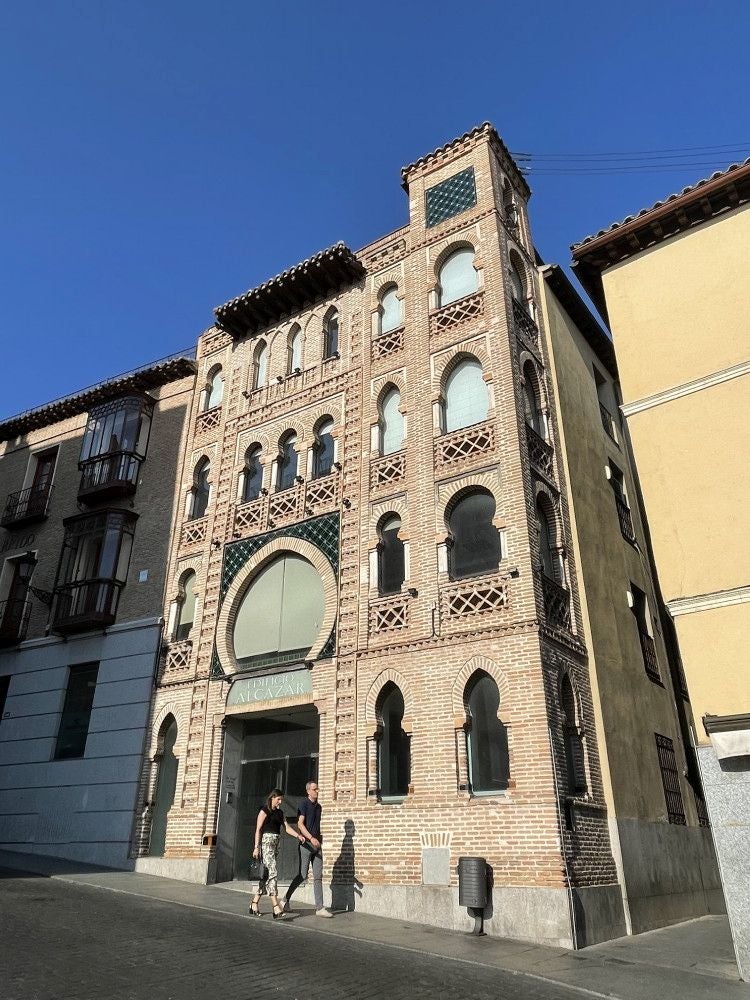 En la calle de Carlos V persiste la fachada neomudéjar que trazó Álvaro González Saz en 1915 para un flamante hotel. Entre 1918 y 1933 el edificio acogió el servicio de Telégrafos y la vivienda de su dueño: Eugenio Ortiz Pedraza. Ente 1934 y 1990 se arrendó para dependencias del Estado. Tras la venta, el inmueble acogería sucesivos cambios de propiedad y usos
