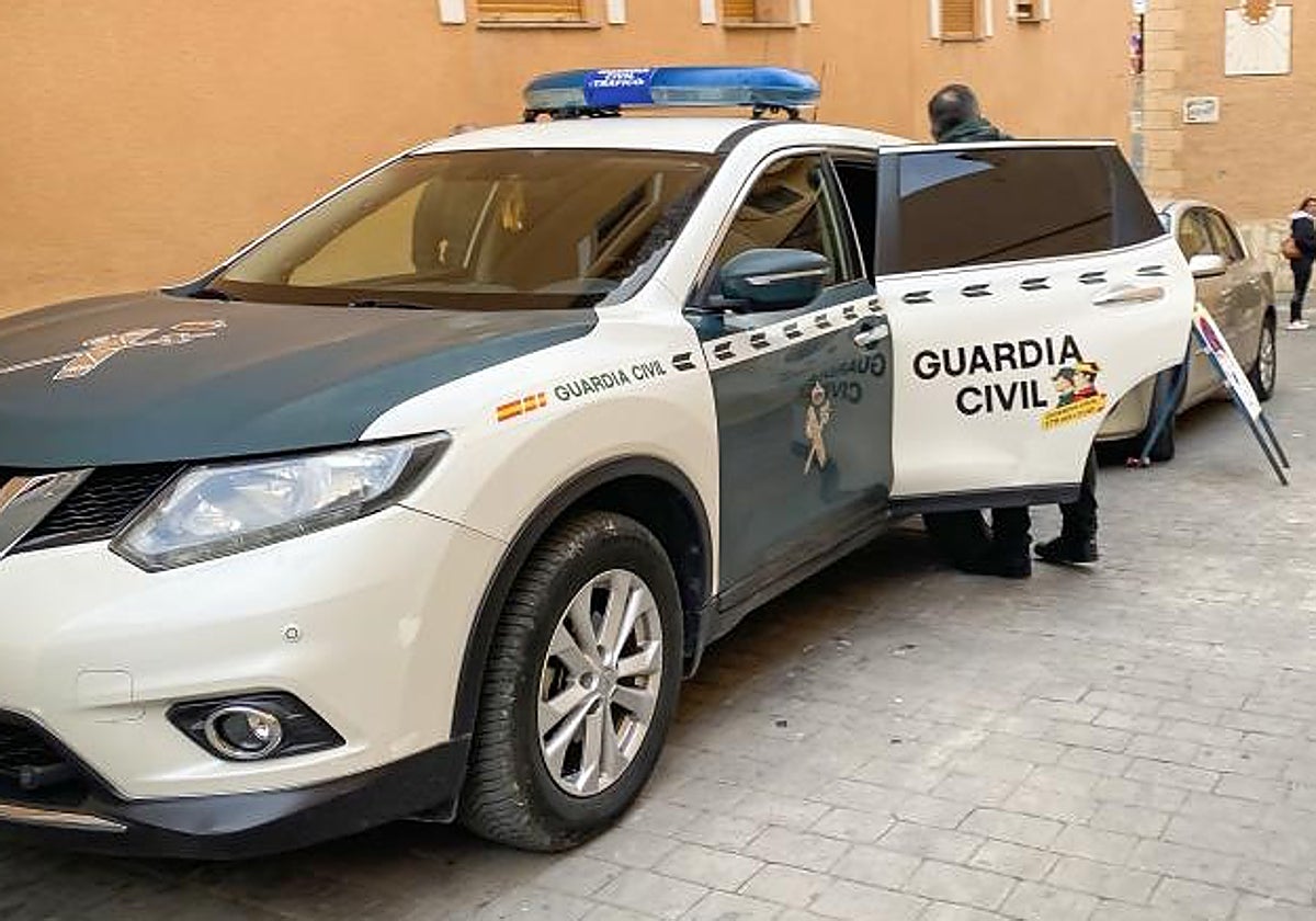 Un guardia civil junto a un coche patrulla durante una intervención