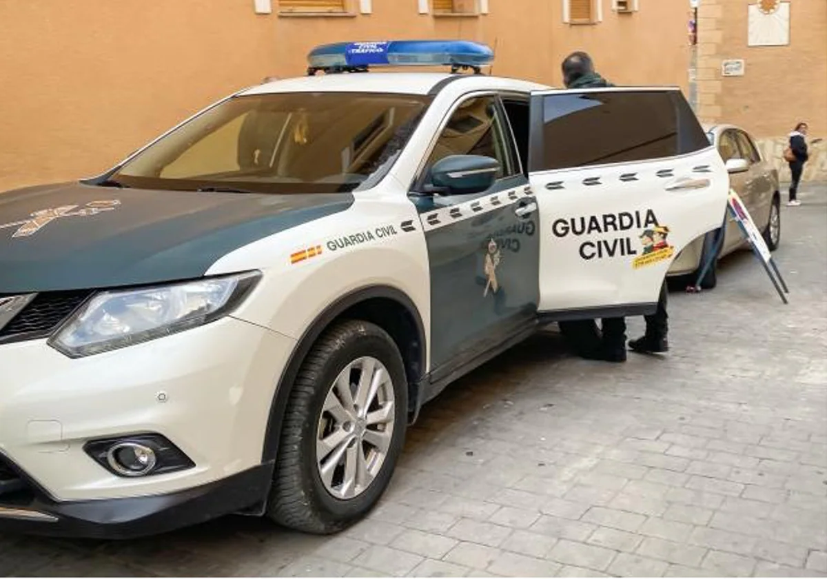 Un guardia civil junto a un coche patrulla durante una intervención