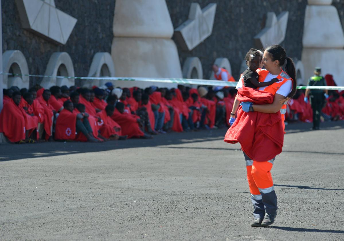 Un miembro de los servicios de emergencia sostiene a un niño llegado en patera a El Hierro