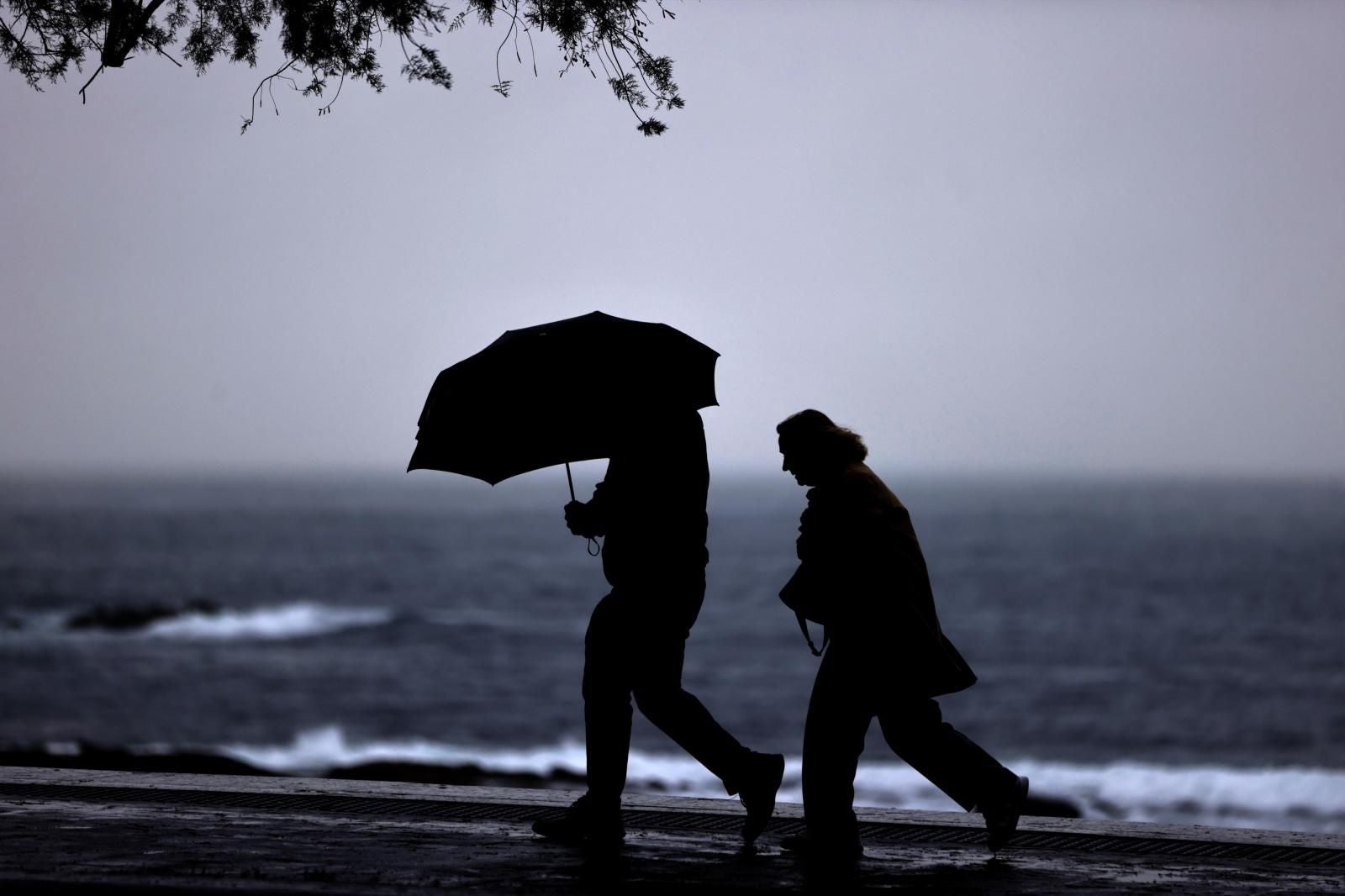 Dos personas caminan este miércoles por el paseo marítimo de La Coruña, donde hay alerta naranja por fenómenos costeros hasta la noche