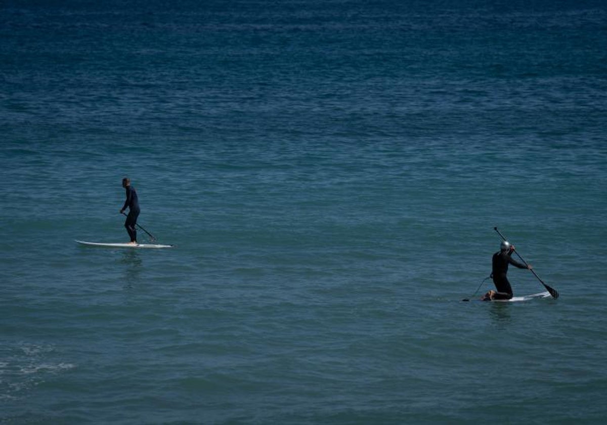 Dos personas practican paddle-surf en la playa del Bogatell (Barcelona)
