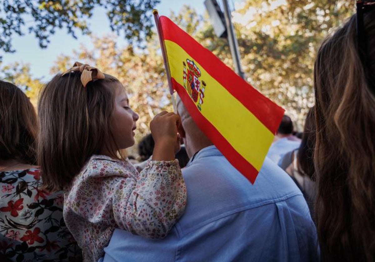 Una niña sujeta la bandera de España durante el desfile del 12 de Octubre