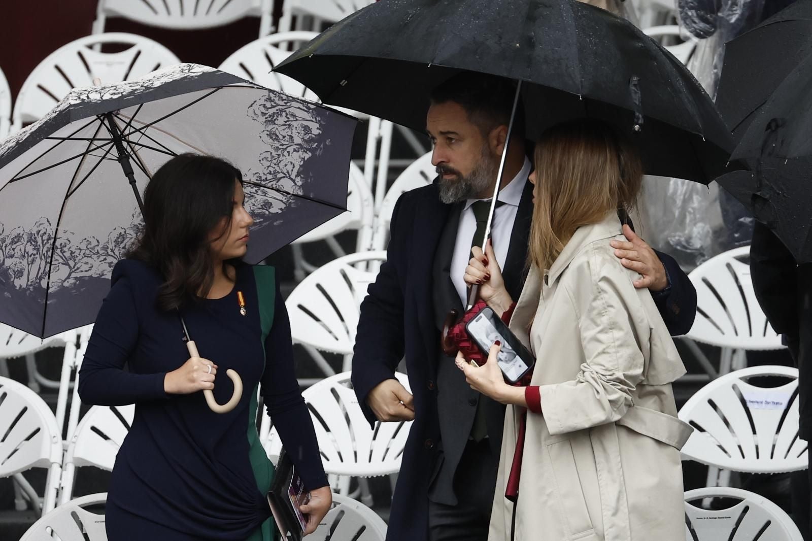 El líder de Vox, Santiago Abascal junto a la portavoz del partido en el Congreso, Pepa Millán, también refugiados por la lluvia a su llegada al acto