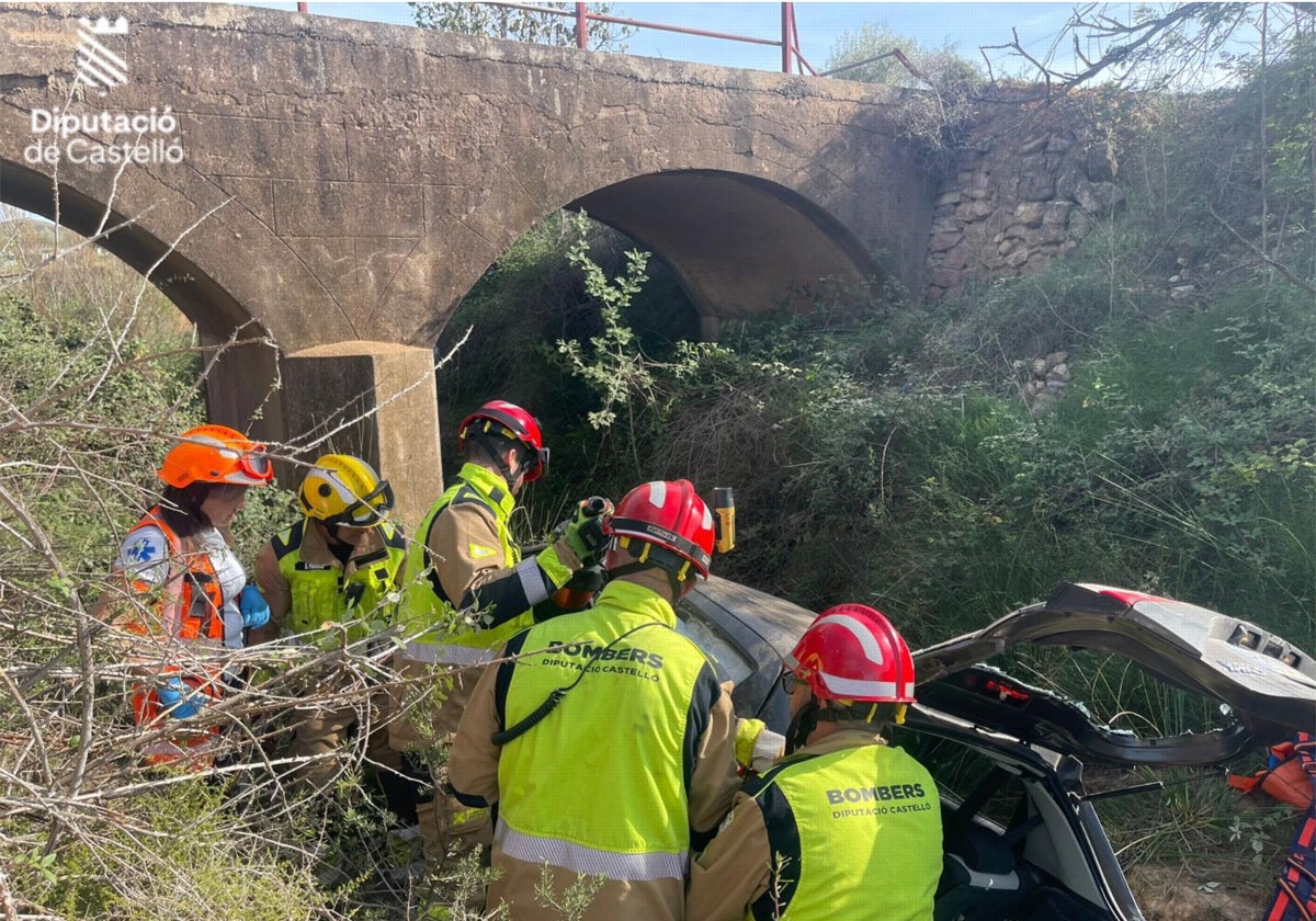 Bomberos junto al coche que ha caído por un barranco junto al puente en Segorbe (Castellón)