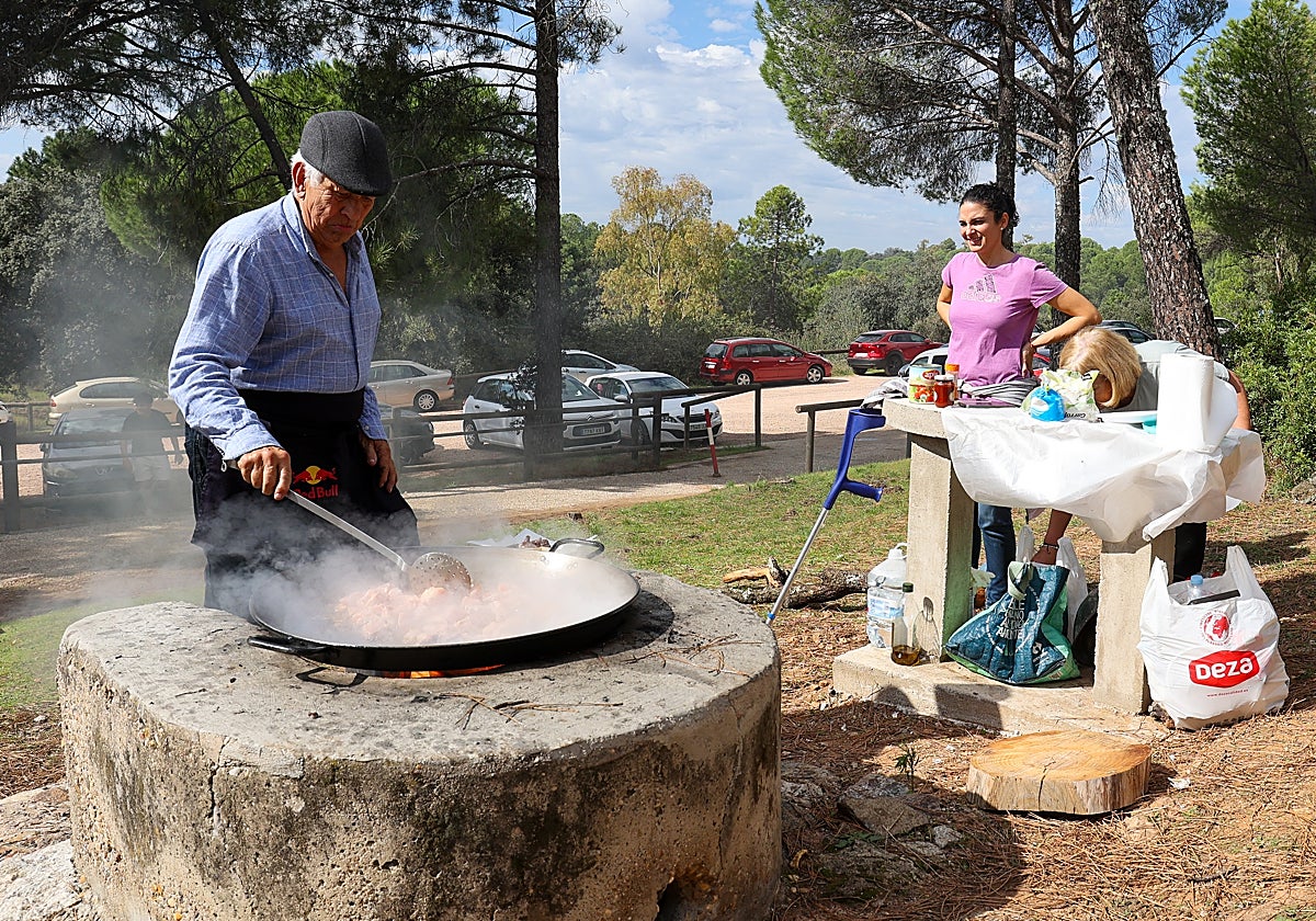 Un hombre mueve el arroz en un merendero de la sierra de Córdoba ante la mirada de sus familiares