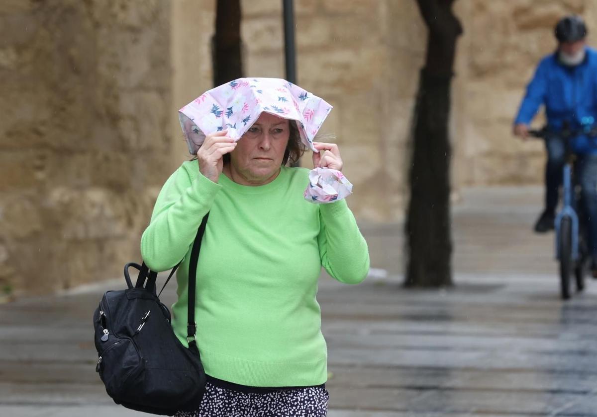 Una mujer se cubre de la lluvia con un pañuelo.