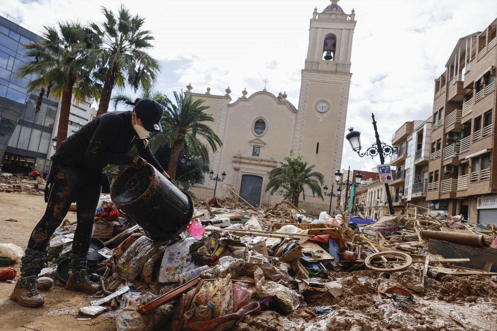 Un voluntario apila basura durante la limpieza de una de las calles de la localidad de Paiporta tras el paso de la DANA