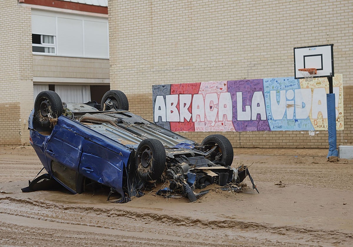 imagen de un coche volcado frente al colegio público del barrio de Parque Alcosa, en Alfafar