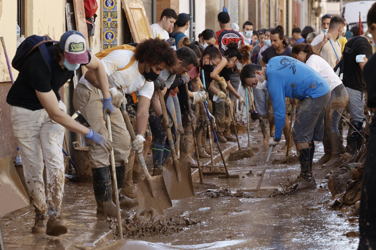 Varias personas retiran el lodo acumulado en una calle de la localidad valenciana de Paiporta, Valencia