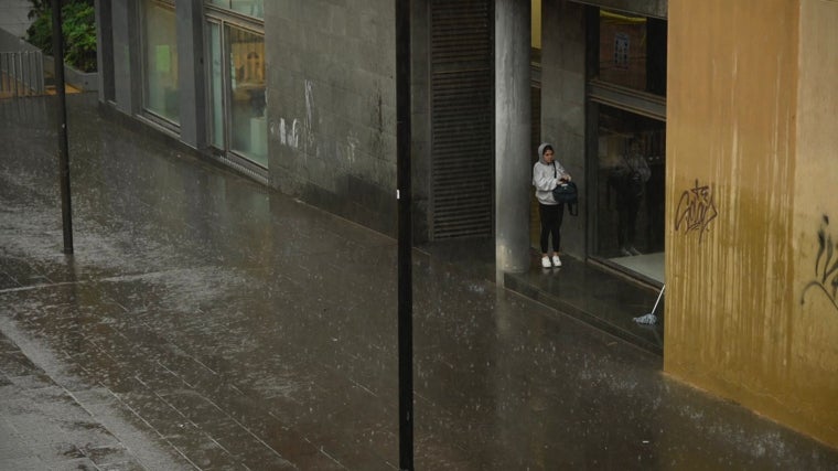 Una joven se resguarda de la fuerte lluvia, este lunes, en Barcelona