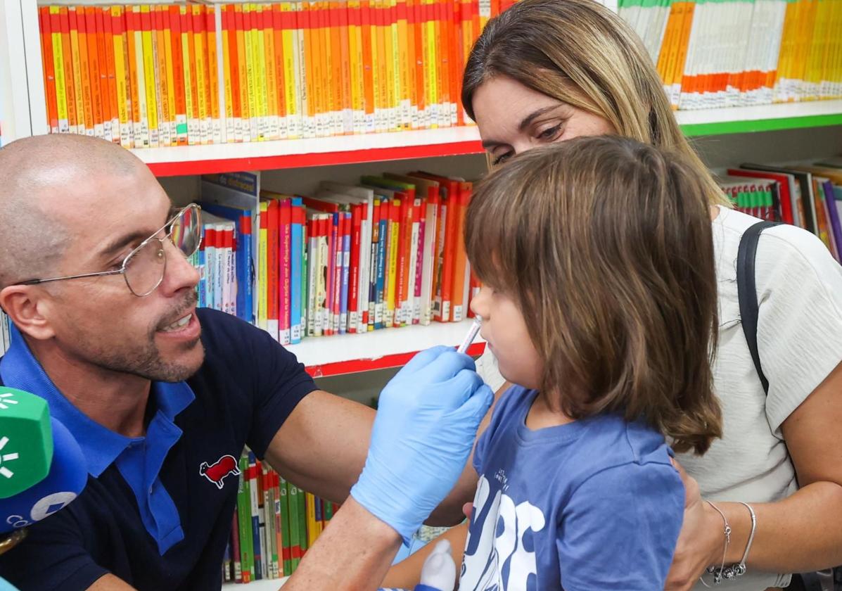 Un sanitario administra la vacuna de la gripe vía intranasal a una niña en un colegio