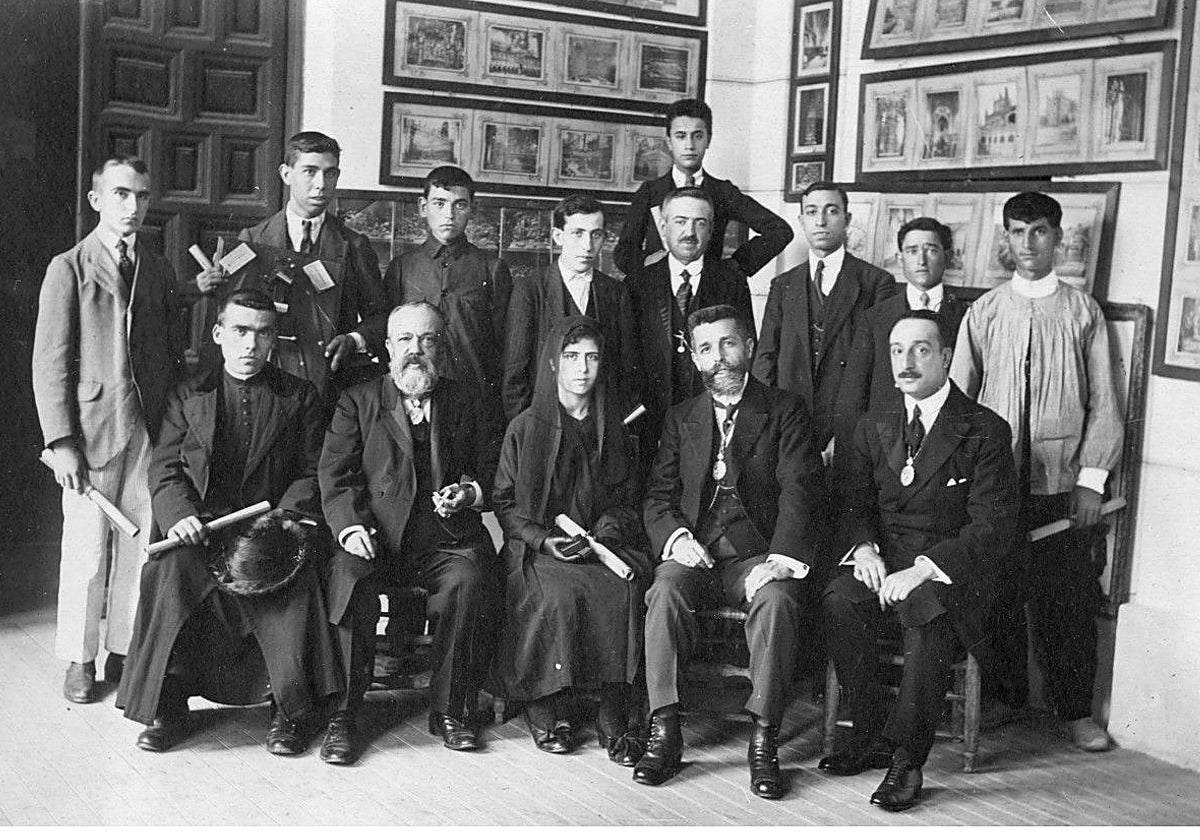 Delante, el primero sentado a la derecha, Álvaro González Saz (1883-1936) el día de su discurso de entrada en la Real Academia de Bellas Artes y Ciencias Históricas de Toledo (30-junio-1918). A su lado, el académico, Adolfo Aragonés de la Encarnación y, el segundo por la izquierda, el director Rafael Ramírez de Arellano. Con un diploma en la mano son los premiados de distintos centros por la institución en la galería del Ayuntamiento. Fotografía de Rodríguez