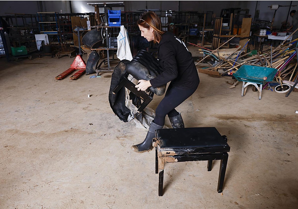 Una mujer recoge enseres en una empresa afectada por los daños causados por la DANA en Valencia