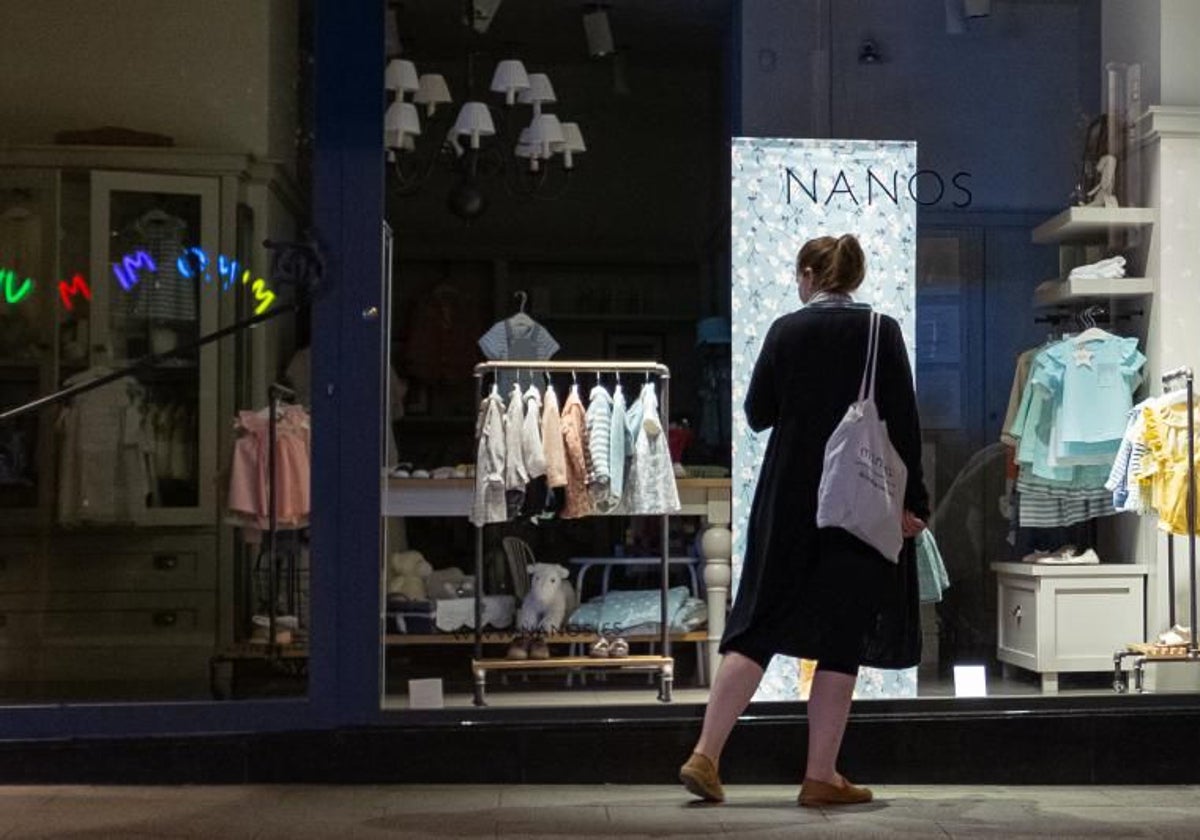 Una mujer mira el escaparate de un comercio de ropa de niños, en Santiago