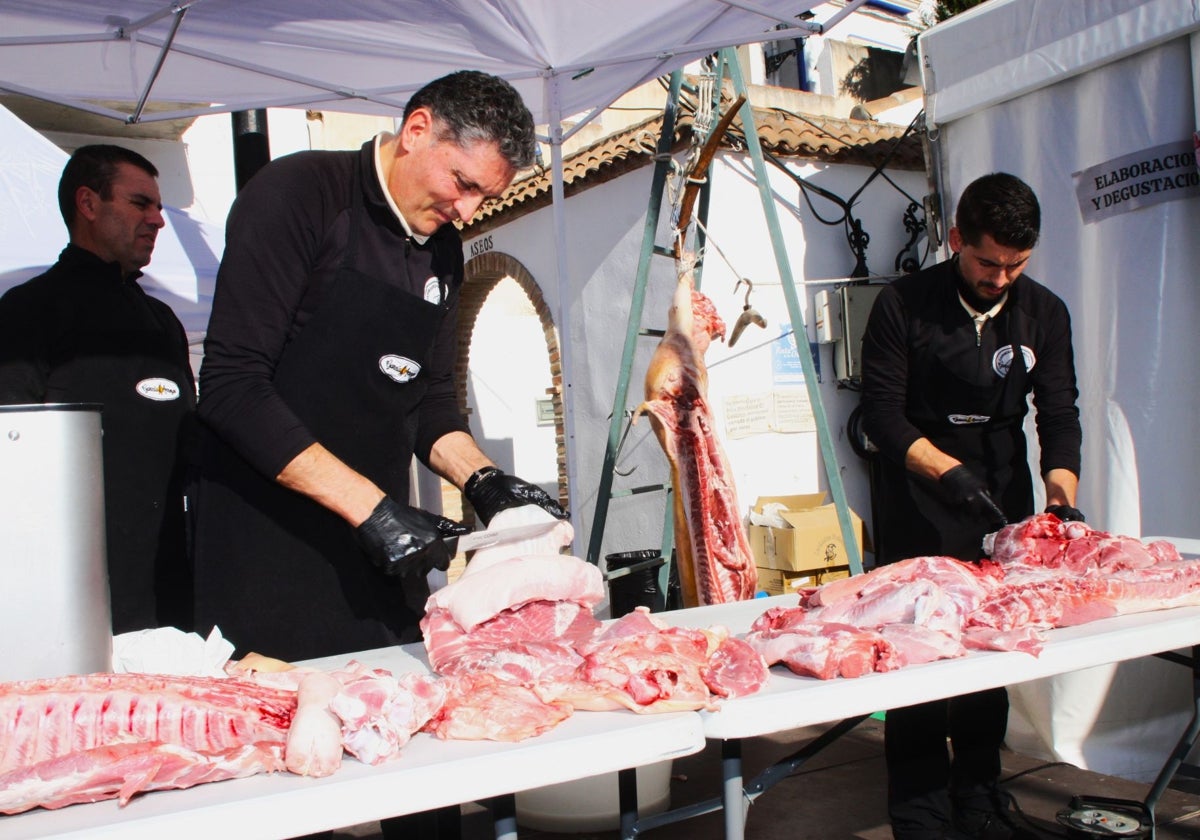 Dos carniceros trocean la carne de un cerdo