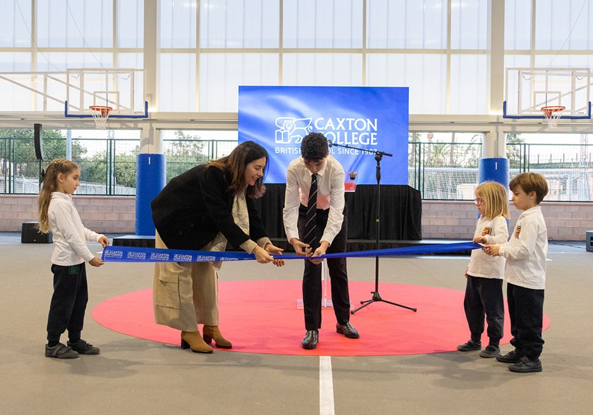 Marta Gil, directora de Caxton College junsto a alumnos del centro cortando la cinta inaugural de pabellón deportivo