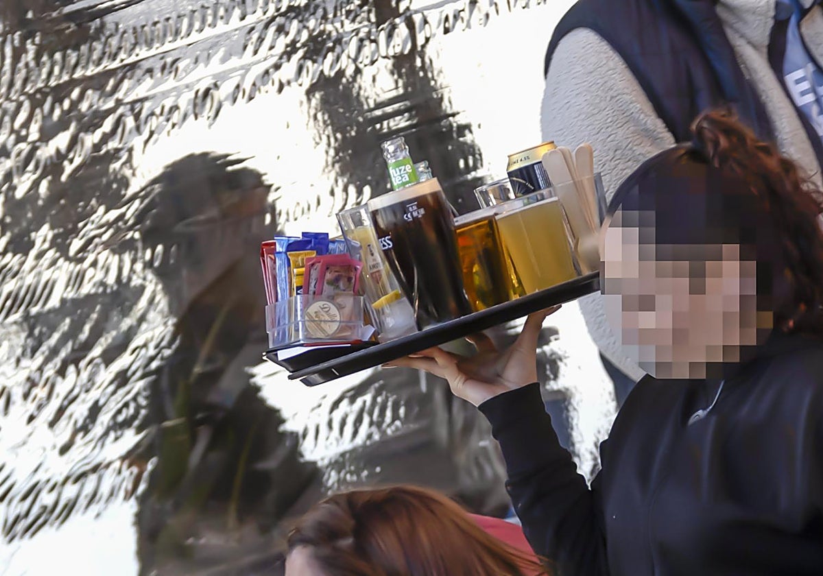 Imagen de archivo de una camarera sirviendo refrescos a una mesa de un bar