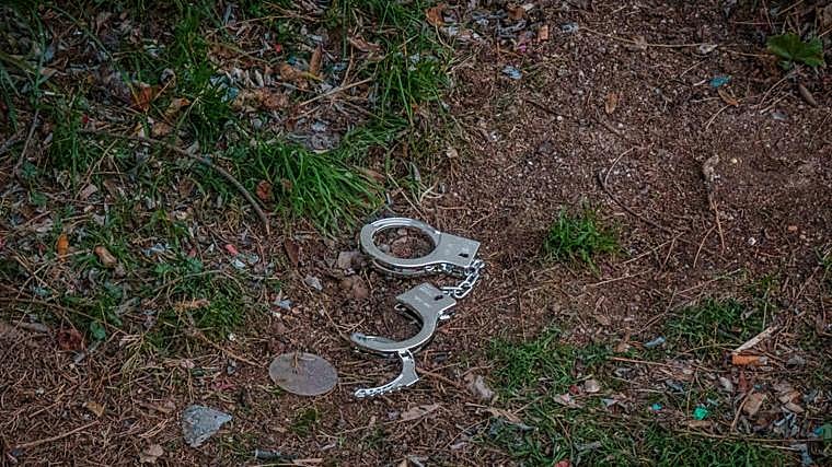 Unas esposas tiradas en el suelo en mitad de una zona ajardinada, también en el barrio de Puente de Vallecas