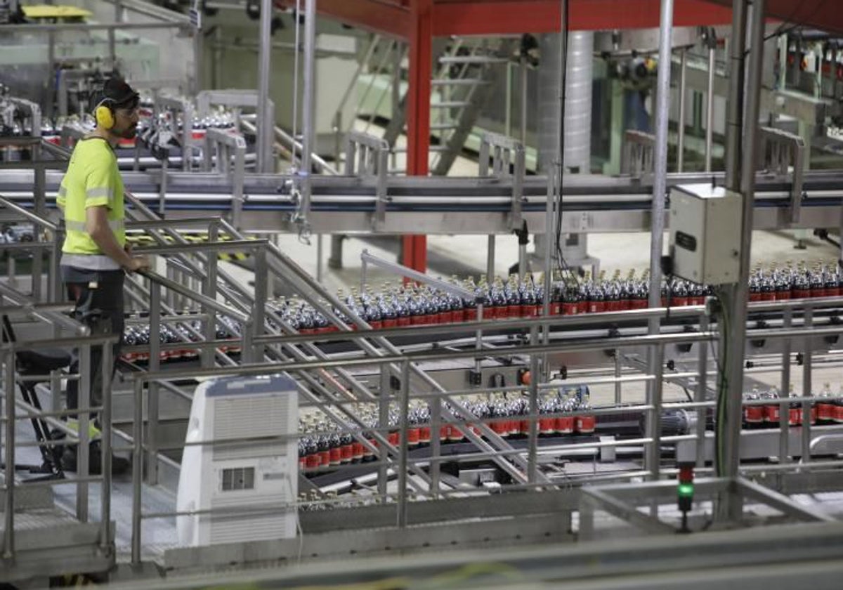 Un operario revisa la cadena de producción en la fábrica de Coca-Cola de Sevilla