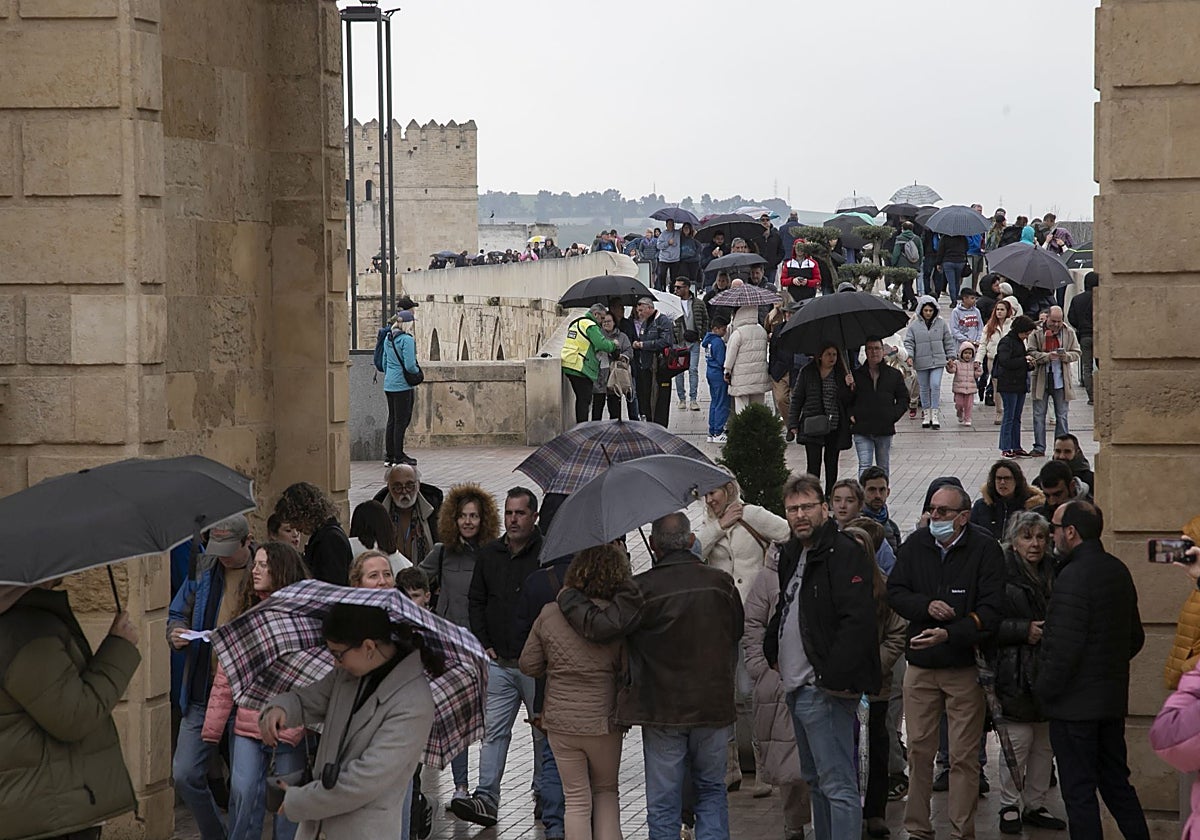 Turistas protegiéndose de la lluvia este viernes en la zona de la Puerta del Puente