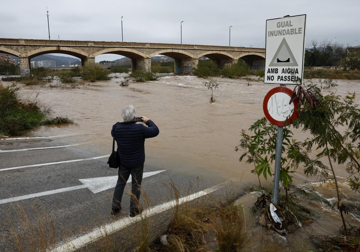 Una persona toma una imagen del caudal del río Palancia a su paso por Sagunto cuando varias carreteras de las provincias de Valencia y Castellón están cortadas por la lluvia