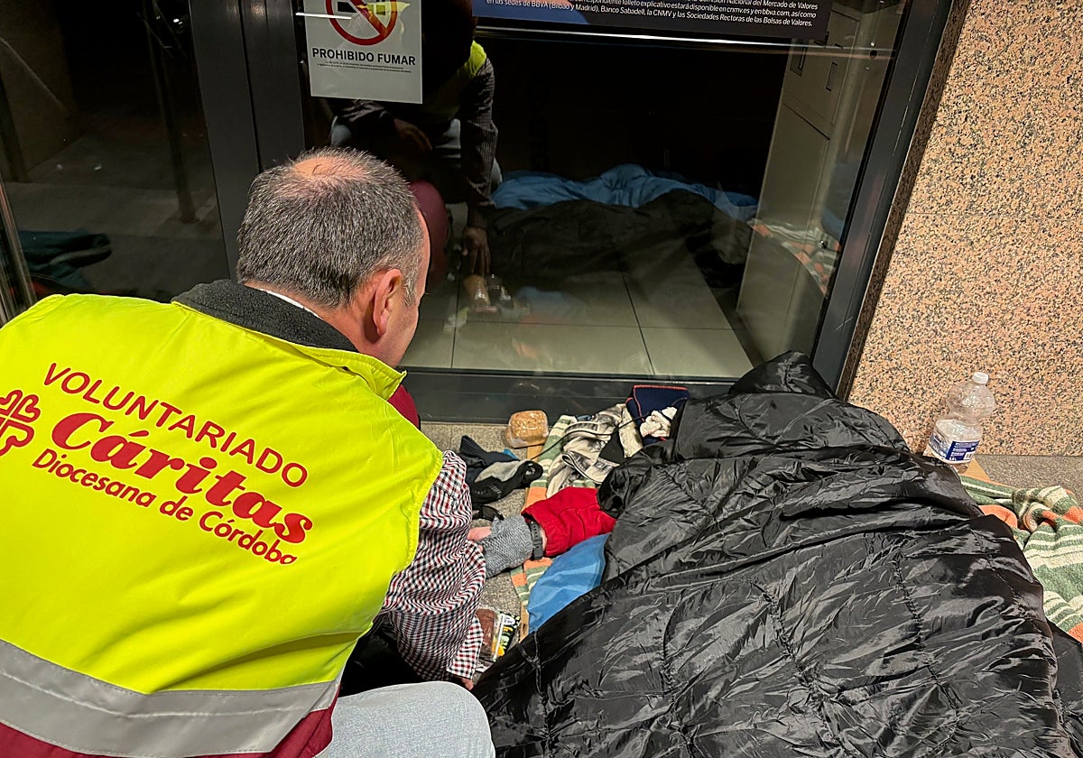 Un voluntario de Cáritas junto a una persona que vive en la calle