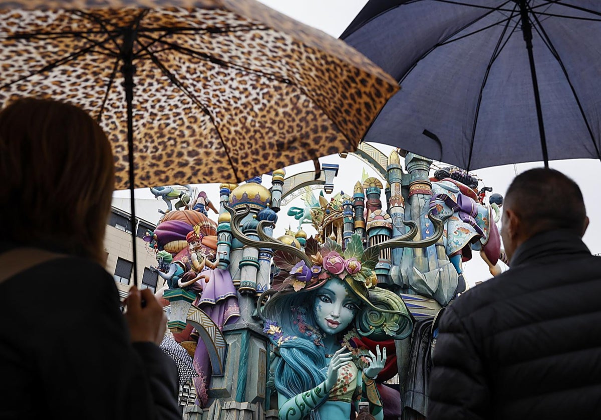 Dos personas se protegen de la lluvia con paraguas mientras contemplan la falla  de Convento Jerusalén