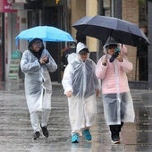 Tres turistas pasean por Córdoba bajo la lluvia