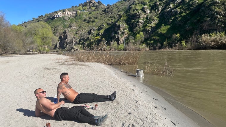 Con el torso desnudo, estos dos amigos toman el sol en la 'playa'