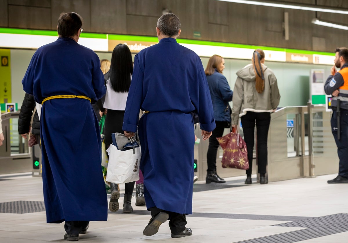 Dos personas vestidas de nazarenos en el Metro de Málaga