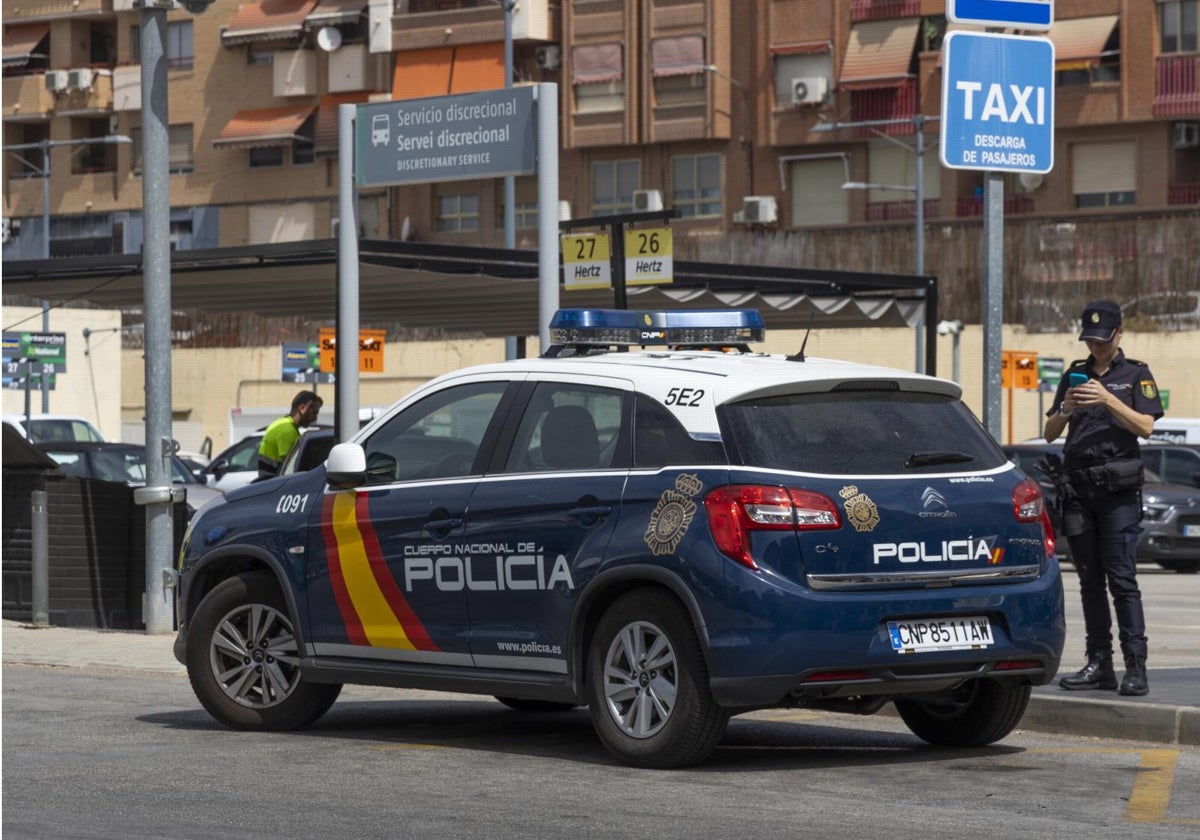 Un agente de la Policía Nacional junto a un coche patrulla