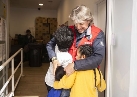 Imagen secundaria 1 - Los asistentes esperan en fila para recibir el número de su turno para comer; Tino, quien organiza el acceso al Comedor Social San Juan Bautista, con la pequeña Anyelis y sus dos hermanos; y otro de los usuarios, ya sentado a la mesa
