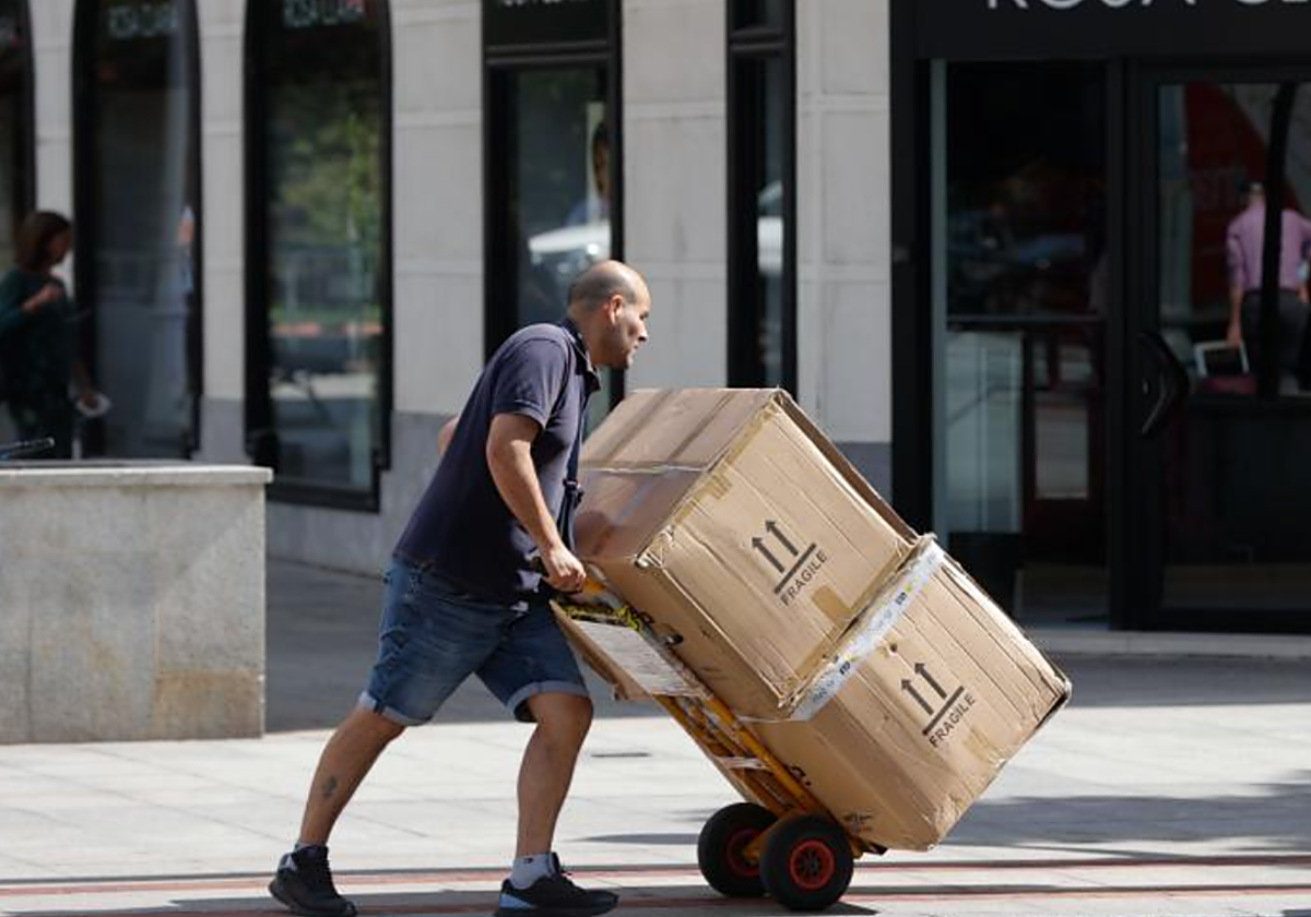 Un transportista traslada la mercancía a un comercio en foto de archivo