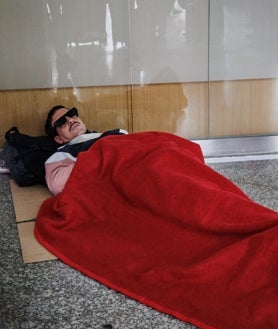 Imagen secundaria 2 - Un agente de la UIP pide el billete a los pasajeros en uno de los controles de acceso; largas colas en uno de los accesos a los trenes de media y larga distancia; y un joven duerme aún a media mañana tapado con una manta de Cruz Roja