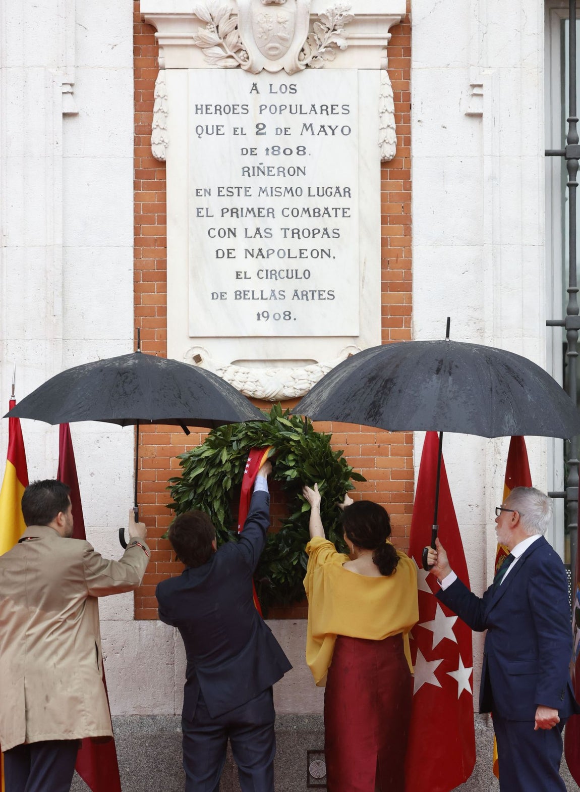 La presidenta de la Comunidad de Madrid, Isabel Díaz Ayuso, junto con el alcalde de la capital, José Luis Martínez-Almeida, acceden a la Puerta del Sol por la calle Correo para depositar una corona de laurel sobre la placa en la fachada de la Real Casa de Correos que recuerda a los héroes del 2 de mayo de 1808.