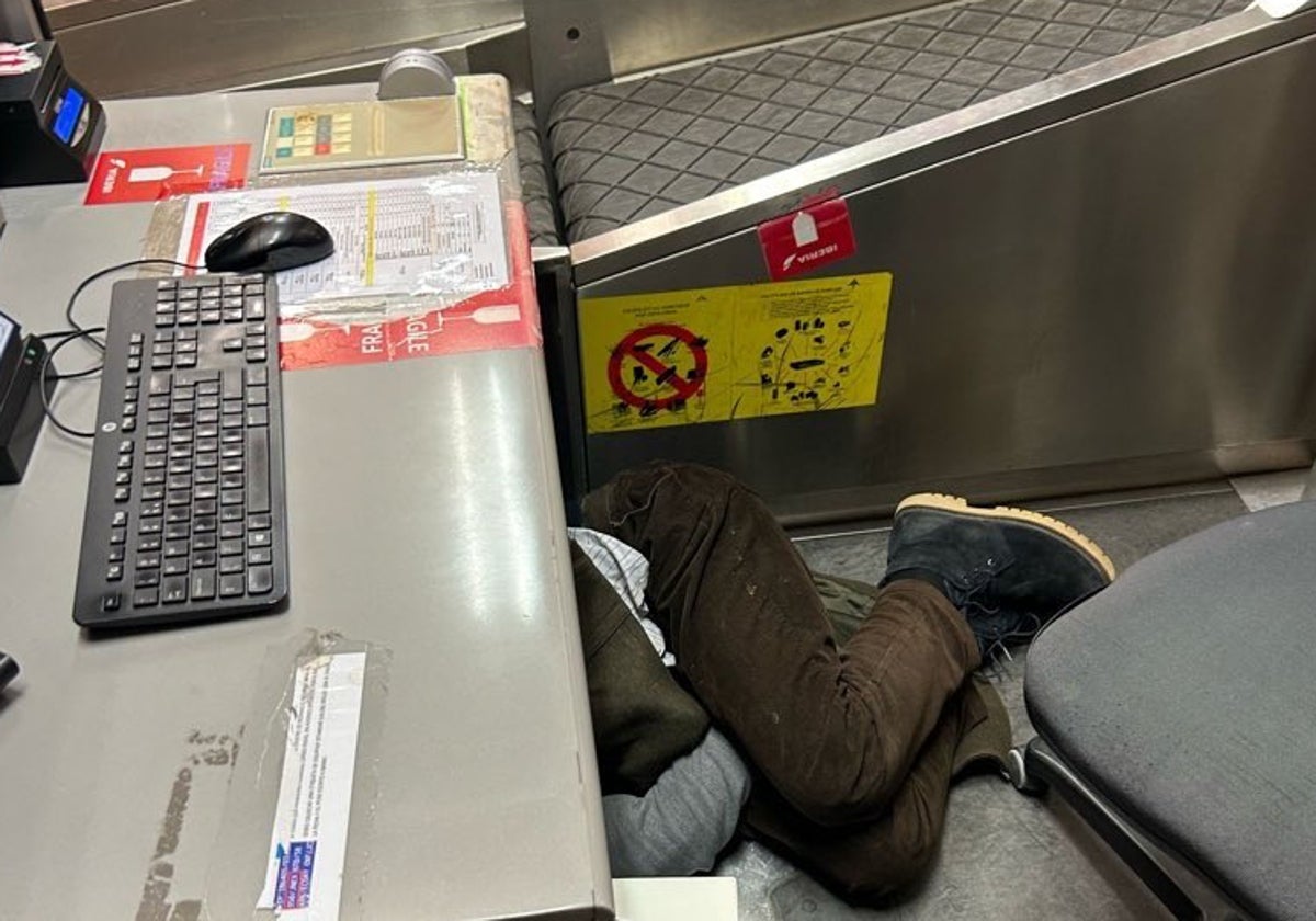 Un sintecho duerme bajo un mostrador de facturación de la T4 de Barajas