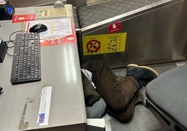 Un sintecho duerme bajo un mostrador de facturación de la T4 de Barajas