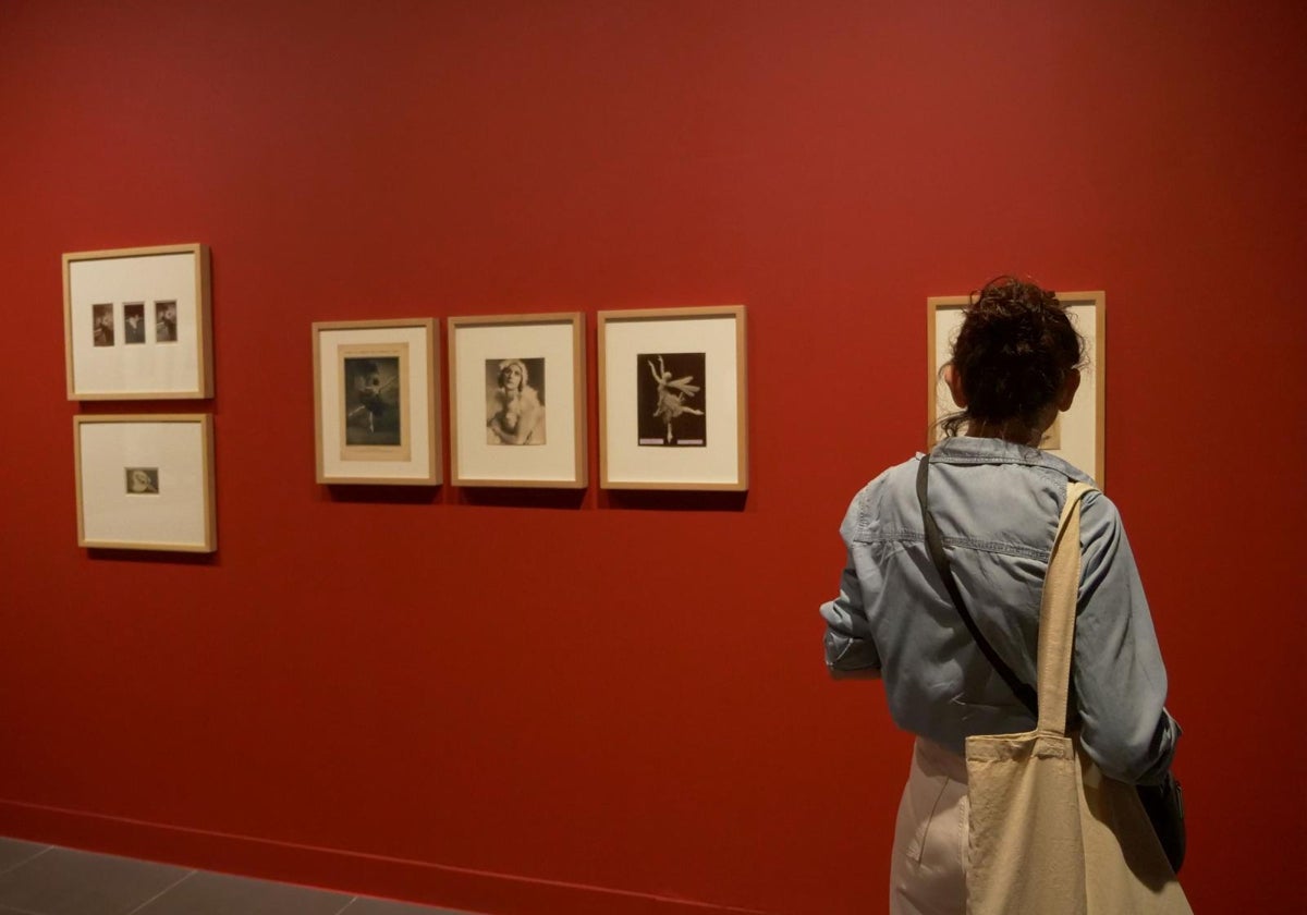 Una mujer observa varios cuadros de la exposición