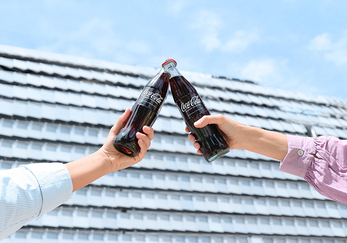 Imagen de dos personas brindando con botellines de Coca Cola frente al Roig Arena
