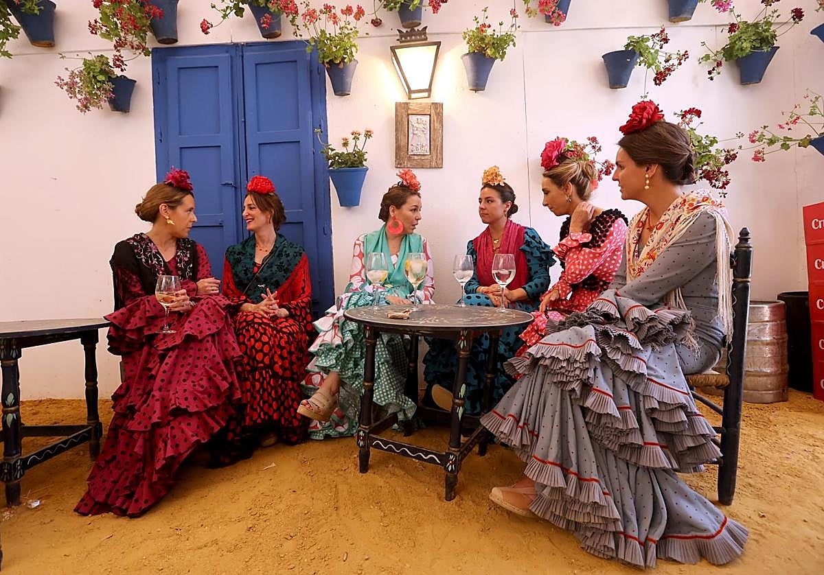 Un grupo de mujeres vestidas de gitanas en una caseta de la Feria