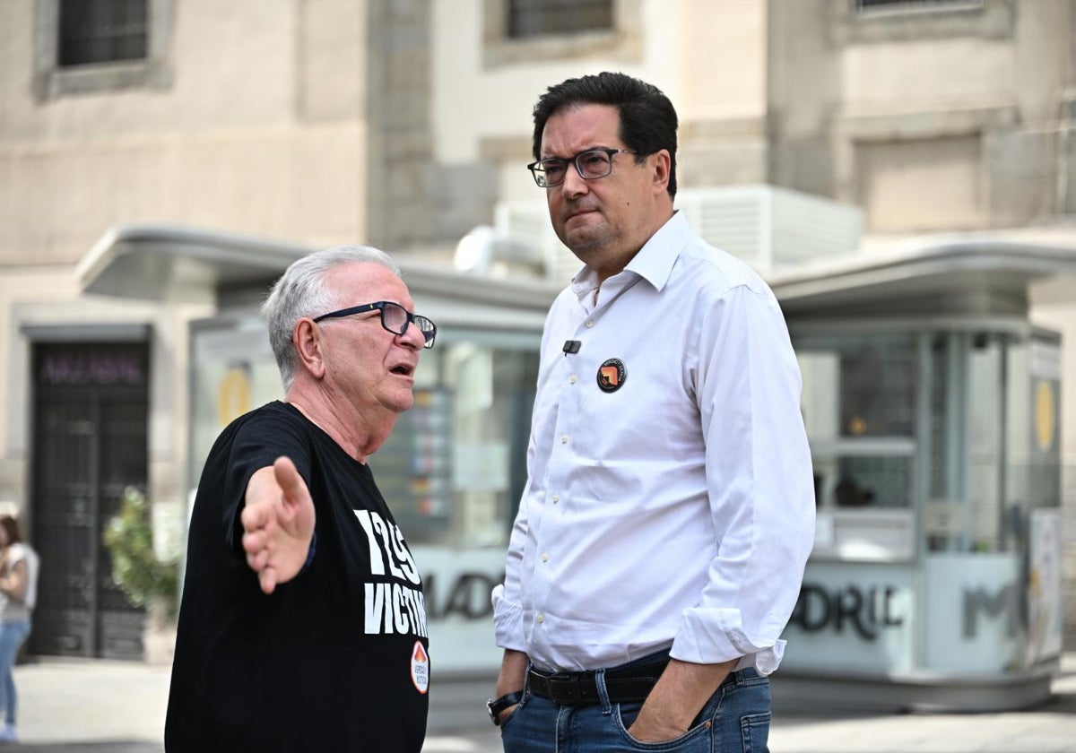 El ministro de Transición Digital, Óscar López, junto a un manifestante por las muertes en las residencias de Madrid durante la pandemia