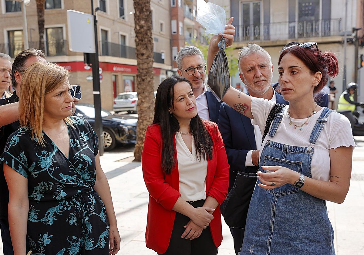 Imagen de una vecina de Catarroja, este miércoles, con una bolsa de aguas fecales ante la delegada del Gobierno, Pilar Bernabé; la alcaldesa de Catarroja, Lorena Sirvent; y el ministro de Política Territorial, Ángel Víctor Torres