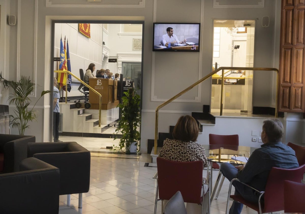 Dos personas siguen una sesión plenaria de la Diputación de Alicante