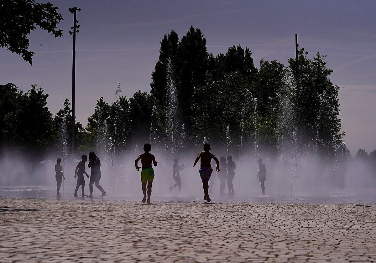 Un grupo de niños se refrescan en la playa de Madrid Río