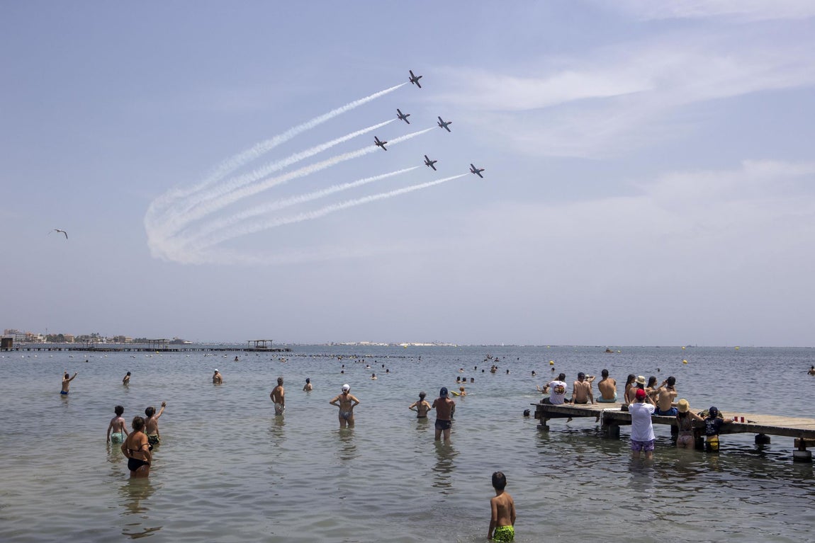 Niños y familias observan con asombro el paso de los aviones desde la playa