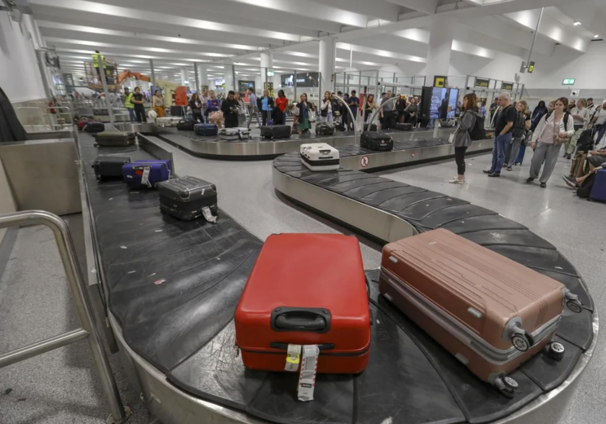 Pasajeros esperan a su equipaje en la terminal de llegadas del aeropuerto de Sevilla en foto de archivo