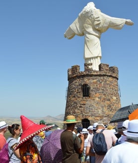 Imagen secundaria 2 - Sobre estas líneas, los fieles se resguardan del sol con paraguas y sombreros en el cerro del Mogorro