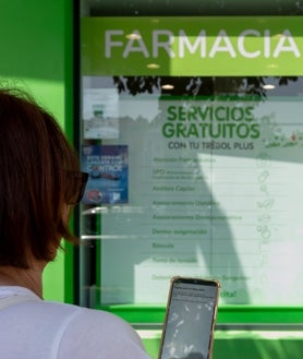 Imagen secundaria 2 - Dos mujeres pasean por la calle de Suecia, mientras una tercera usa el móvil en compañía de su perro; en las fotos pequeñas, Piluca se ha visto obligada a contratar fibra óptica en su frutería ante la imposibilidad de poder cobrar con el datáfono; y una vecina no puede abrir la receta electrónica para retirar los medicamentos de la farmacia